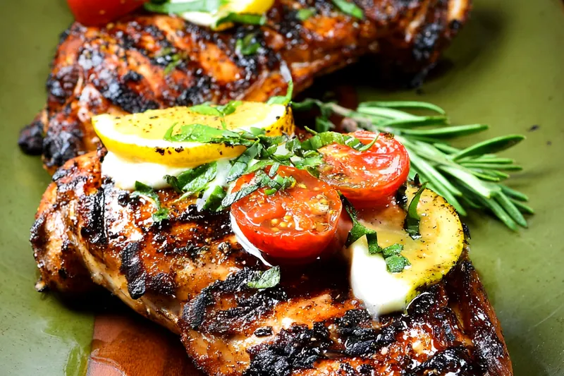 Fresh chicken breasts, ripe avocados, tomatoes, lime, garlic, spices, and Monterey Jack cheese arranged on a marble cutting board